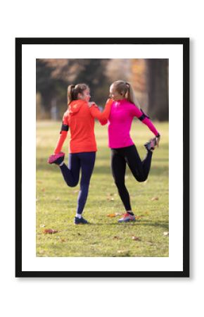 Sporty female athletes are warming up before jogging, doing lower body stretching in the park
