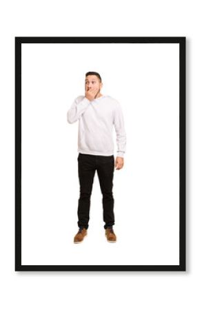 Full body adult latin man cut out isolated thoughtful looking to a copy space covering mouth with hand.