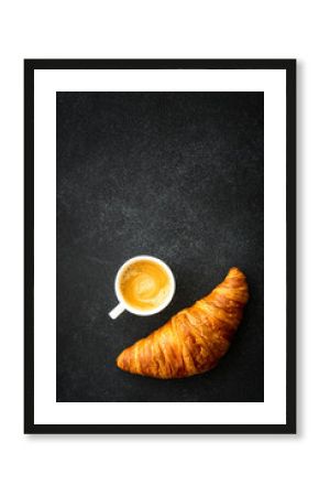 Croissant and cup of coffee at black background. Top view with copy space, vertical image.
