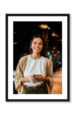 Hispanic young woman smiling and using cellphone during offline meeting