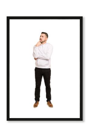 Full body adult latin man cut out isolated looking sideways with doubtful and skeptical expression.