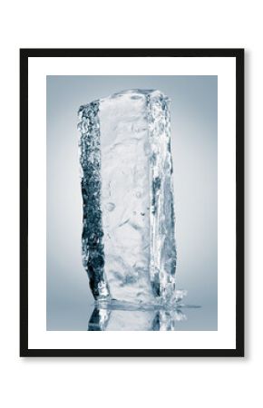 Crystal clear natural ice block in light blue tones on a white reflective surface.