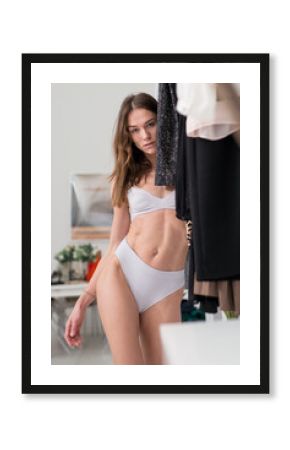Woman in her underwear at home by the clothes closet
