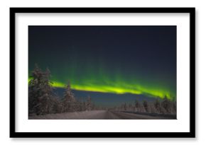 picture of massive multicoloured green vibrant Aurora Borealis, Aurora Polaris, also know as Northern Lights in the night sky over winter landscape with road
