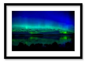 Northern lights dancing over calm lake. Farnebofjarden national park in Sweden.