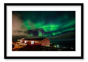 Green bright northern lights hidden by the clouds over living houses at the fjord, Nuuk city, Greenland