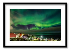 Green bright northern lights hidden by the clouds over the Inuit village at the fjord, Nuuk city, Greenland