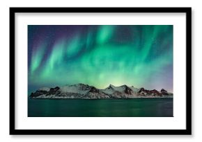 Blue and green glowing northern lights over norwegian winter landscape