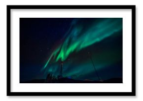 Green waves of Aurora Borealis with shining stars over the mountains and radio tower, Nuuk, Greenland