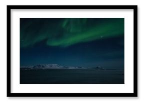 Aurora Borealis over fiord in the Arctic.