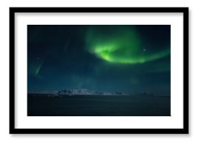 Aurora Borealis over fiord in the Arctic.