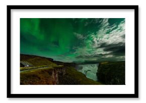 Northern Lights over the Gullfoss waterfall in Iceland. Aurora Borealis in an amazing nightscape. Travel destination with beautiful green lights landscape.