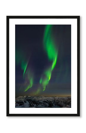 Beautiful northern lights, aurora in the night sky over the snow-covered hills.