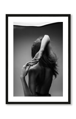 Back view of nude woman with loose hair in black and white photograph