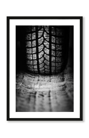 A black-and-white image of the wheel of a passenger car driving on a sandy road. Off-road driving.