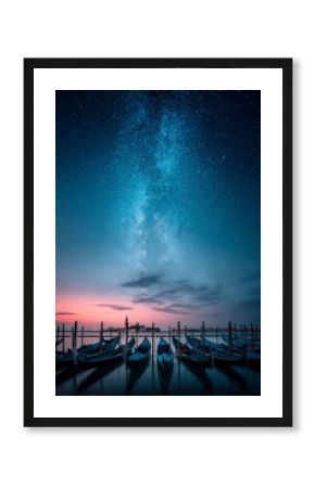 Gondolas in a row and Chiesa di San Giorgio Maggiore in background against milky way on the sky