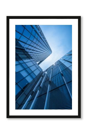 Bottom view of modern skyscrapers in business district against blue sky.