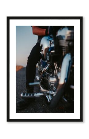 Vertical shot of a person sitting on a motorcycle on the road in the evening