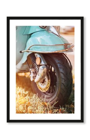 Close up of a disc brake of a vintage light blue retro moped parked on the street.