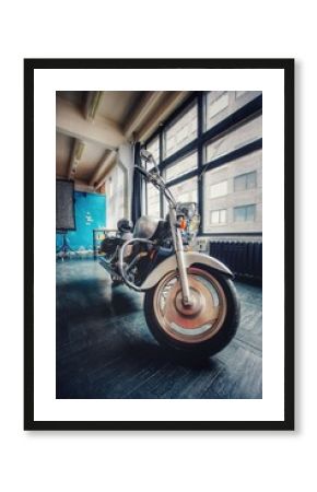 A large silver motorcycle on the black floor. Cruiser chrome