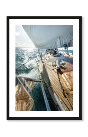 Sloop-rigged modern yacht with wooden teak deck sailing on a clear day. Close-up view to the mast and sails. Jura island, Inner Hebrides, Scotland, UK