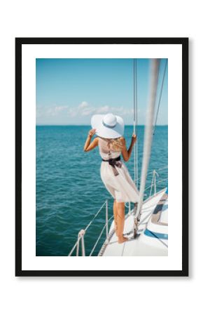 Romantic girl in a hat and dress floats on a white yacht on the sea. Vertical orientation.