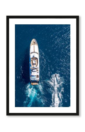 Vertical high angle shot of a private yacht and a small motorboat sailing in the ocean