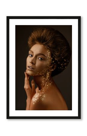 Fashion art portrait of model girl with holiday golden shiny professional makeup. beaty woman with gold metallic body and hair on dark background. Gold glowing skin.