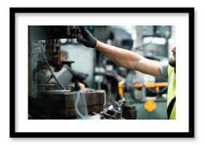 Men industrial engineer wearing a white helmet while standing in a heavy industrial factory behind. The Maintenance looking of working at industrial machinery and check security system setup in fact