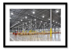 Interior of large warehouse industrial building with parked forklifts, shipping containers, and crates