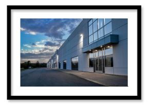 Exterior view of a generic business park building at dusk with multiple high bay units, prefab metal cladding, glazing, aluminum mullions, exterior lights on, nobody