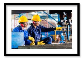 Worker in factory at industrial metal cutting machine