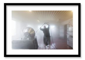 Man using power hose to clean industrial machine