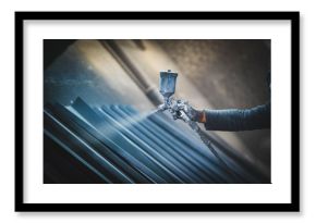Man painting metal products with a spray gun