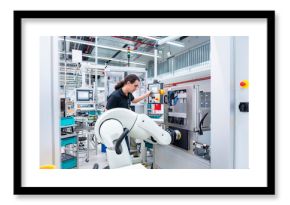Employee operating industrial robot in a production hall