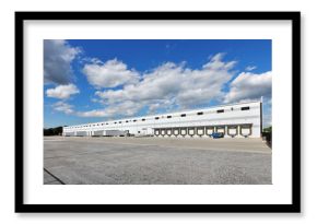 Rear view of large white distribution warehouse industrial building with parking lot