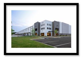 Modern gray industrial warehouse distribution building and parking lot