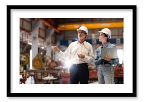 two professional engineer,worker,technician use clipboard discuss work, walk in steel metal manufacture factory plant industry. Black African American man and woman wear hard hat check quality machine