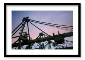 The image captures towering port container cranes against a twilight sky, showcasing the silhouette of the industrial structures.