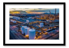 Aerial view oil terminal is industrial facility at night for storage of oil and petrochemical products ready for transport to further storage facilities in city skyline.