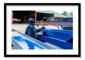 The painter is working to painting the steel structure with spray gun at industrial factory. focus on hand