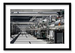 Contemporary hallway with metallic pipelines and industrial equipment located on factory on sunny day