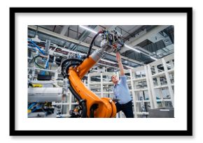 Businessman examining industrial robot in a factory