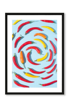 Hot chili dynamic pepper background in the form of a spiral. Hot red, yellow, orange peppers on blue, natural spices, top view, pop-art style with trendy dark shadows