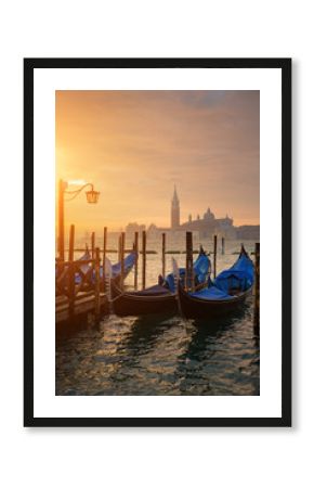 Gondolas by Saint Mark square during sunrise with San Giorgio di Maggiore church in the background in Venice Italy