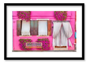 Pink house with pink flowers and plants. Nice bench under windows. Colorful house in Burano island near Venice, Italy