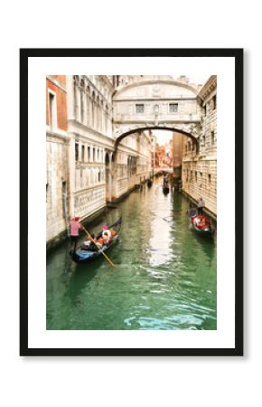 Gondolier carrying tourists in their gondola, by the bridge of sighs in venice, italy at sunset