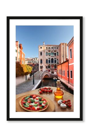 Venice with Italian pizza against canal in Italy