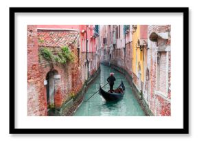 Venetian gondolier punting gondola through green canal waters of Venice Italy