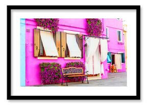 Pink house with pink flowers and plants. Nice bench under windows. Colorful house in Burano island near Venice, Italy